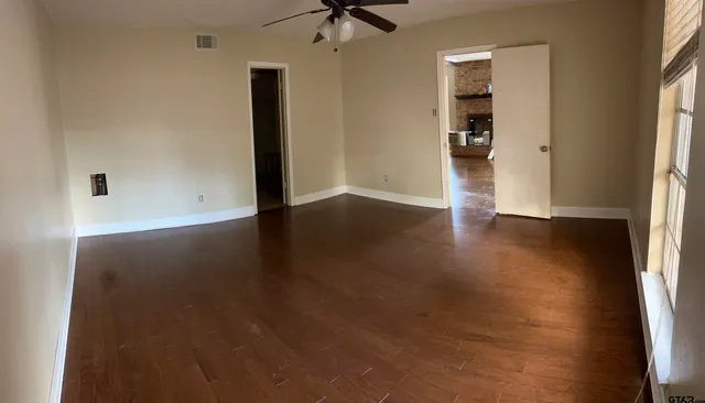 an empty room with wooden floor closet and windows