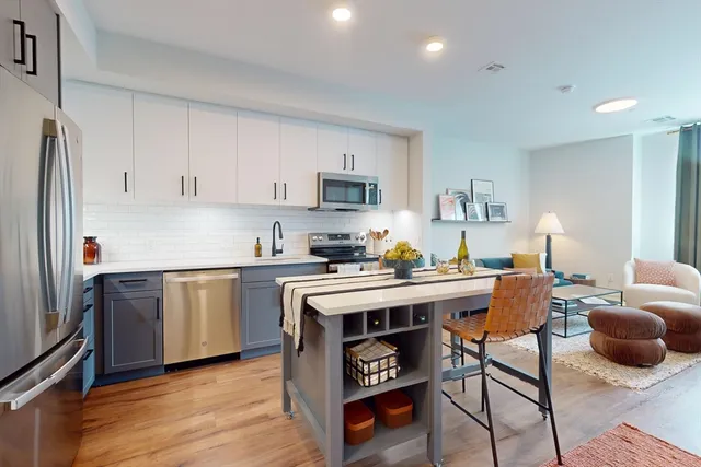 a kitchen with stainless steel appliances granite countertop a stove a sink dishwasher and a refrigerator with wooden floor