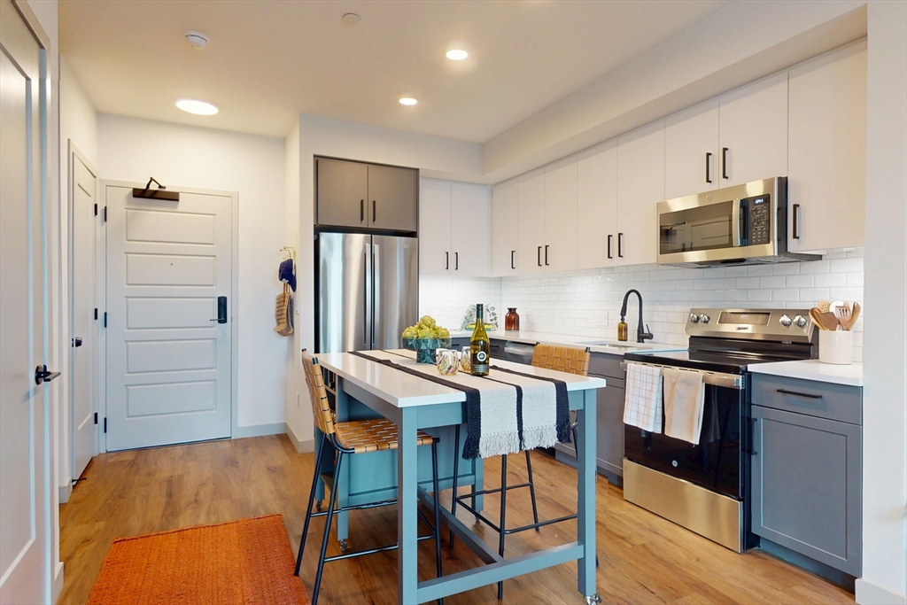 80 Rugg Road, Unit 1301 Boston, MA 02134 - Photo 19 of 20 a kitchen with stainless steel appliances a refrigerator a stove a sink a dining table and chairs