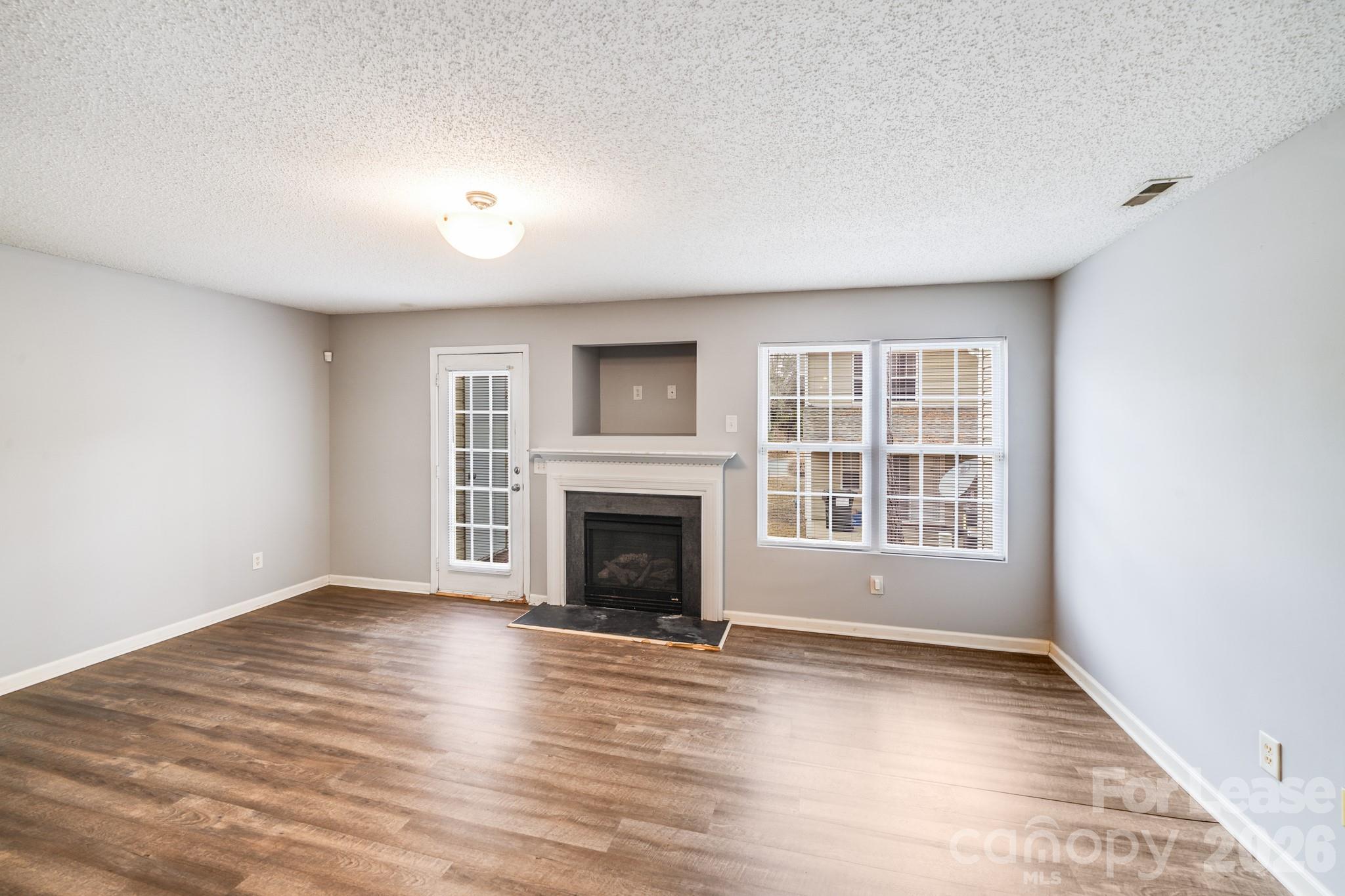3260 Barons Court Road Charlotte, NC 28213 - Photo 12 of 25 an empty room with wooden floor fireplace and windows