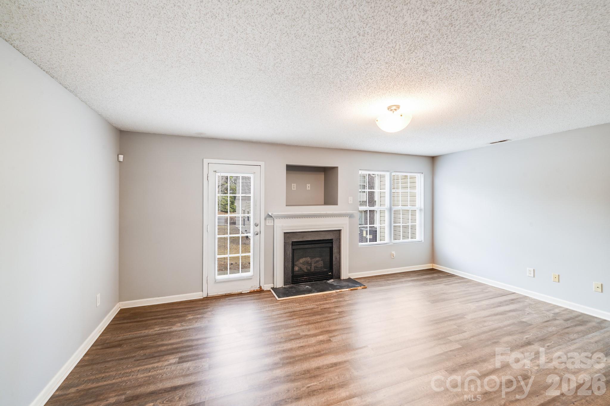 3260 Barons Court Road Charlotte, NC 28213 - Photo 13 of 25 an empty room with wooden floor fireplace and windows