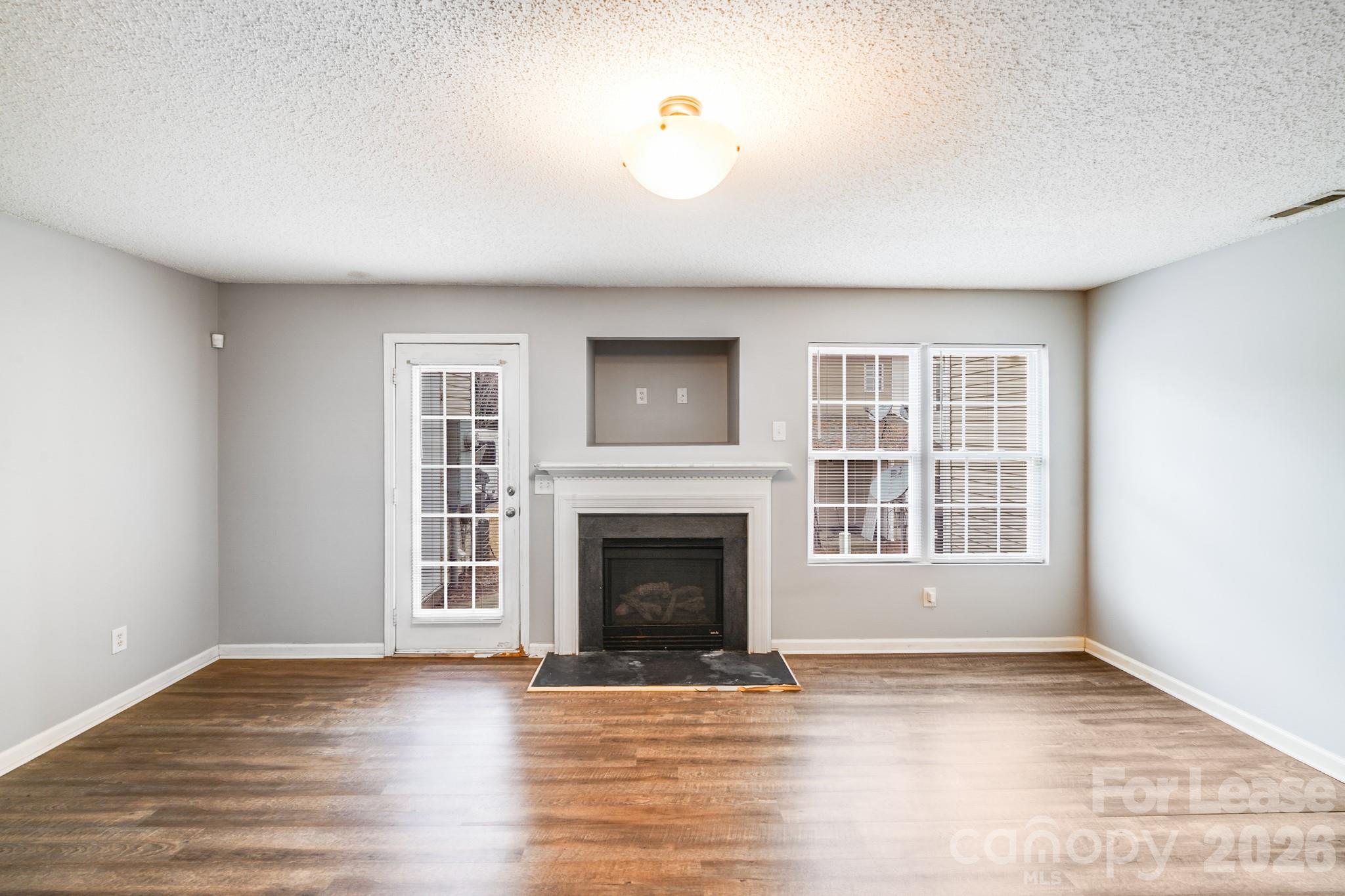 3260 Barons Court Road Charlotte, NC 28213 - Photo 2 of 25 an empty room with wooden floor fireplace and windows