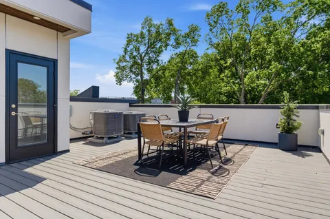 a view of a roof deck with table and chairs with wooden floor and fence