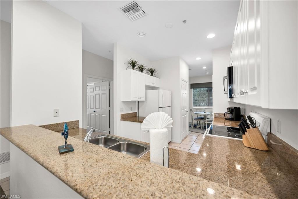 7930 Mahogany Run Lane, Unit 826 Naples, FL 34113 - Photo 10 of 50 a kitchen with granite countertop a sink a stove and cabinets