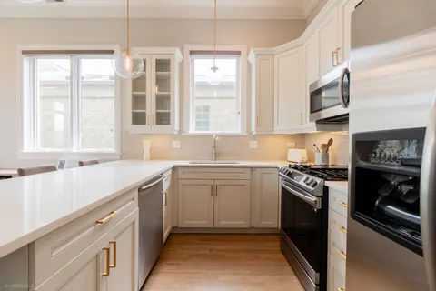 a kitchen with granite countertop a refrigerator stove top oven and sink