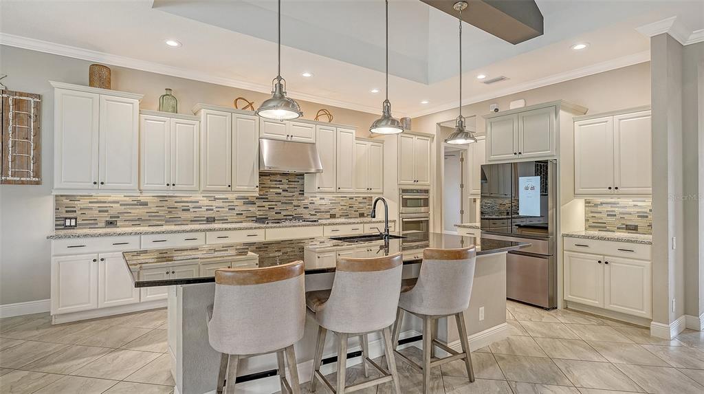 318 Ragdoll Run Bradenton, FL 34212 - Photo 18 of 87 a kitchen with stainless steel appliances kitchen island granite countertop a table chairs and white cabinets