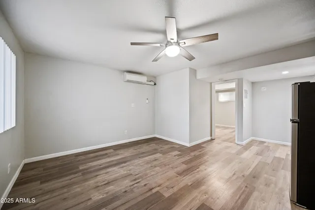 an empty room with wooden floor fan and windows