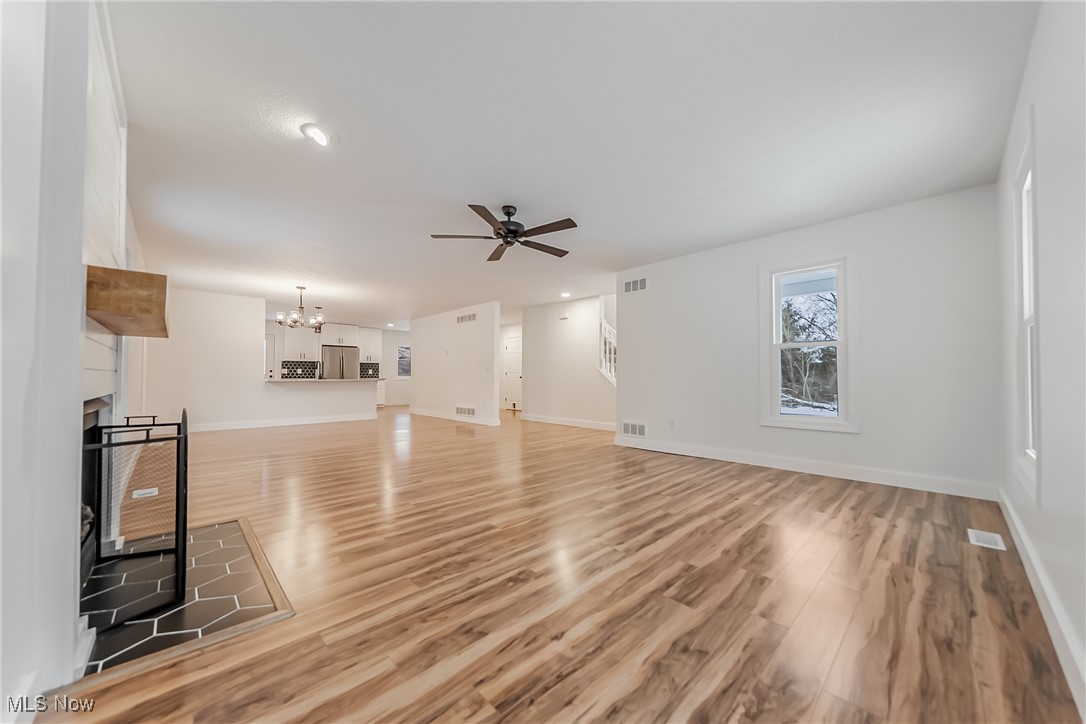 7488 Greenwich Road Seville, OH 44273 - Photo 3 of 37 Unfurnished living room with a multi sided fireplace, a chandelier, light wood-type flooring, ceiling fan, and recessed lighting