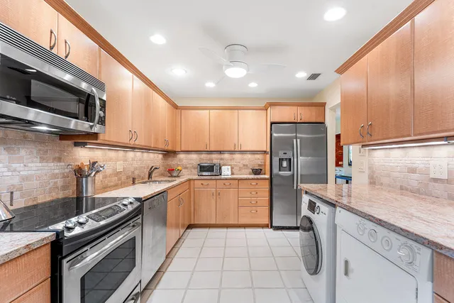a kitchen with stainless steel appliances granite countertop a refrigerator and a stove top oven