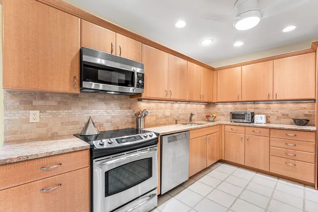 a kitchen with stainless steel appliances granite countertop grey cabinets a stove a sink and a microwave