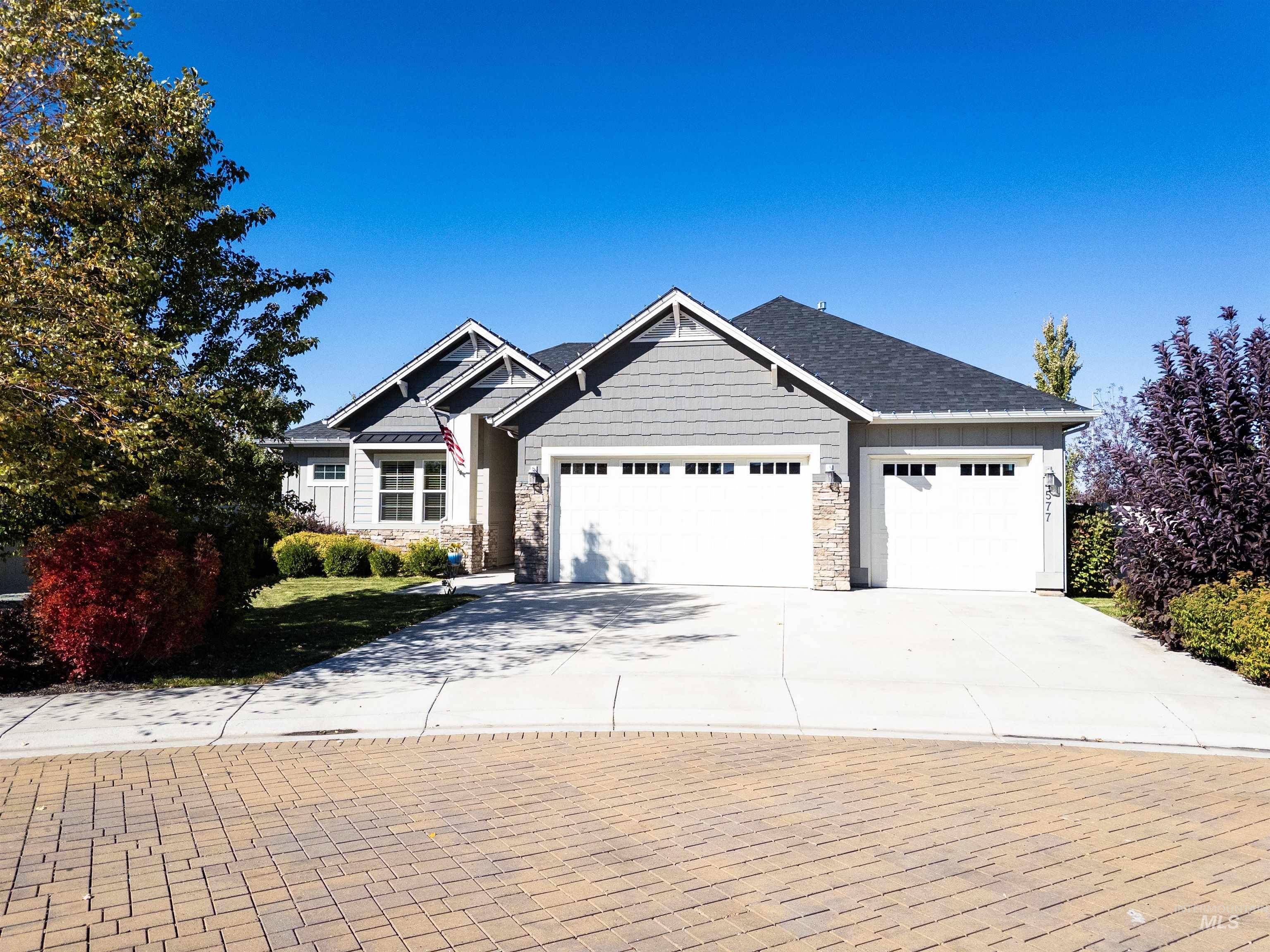 Craftsman-style house with stone siding, driveway, and an attached garage