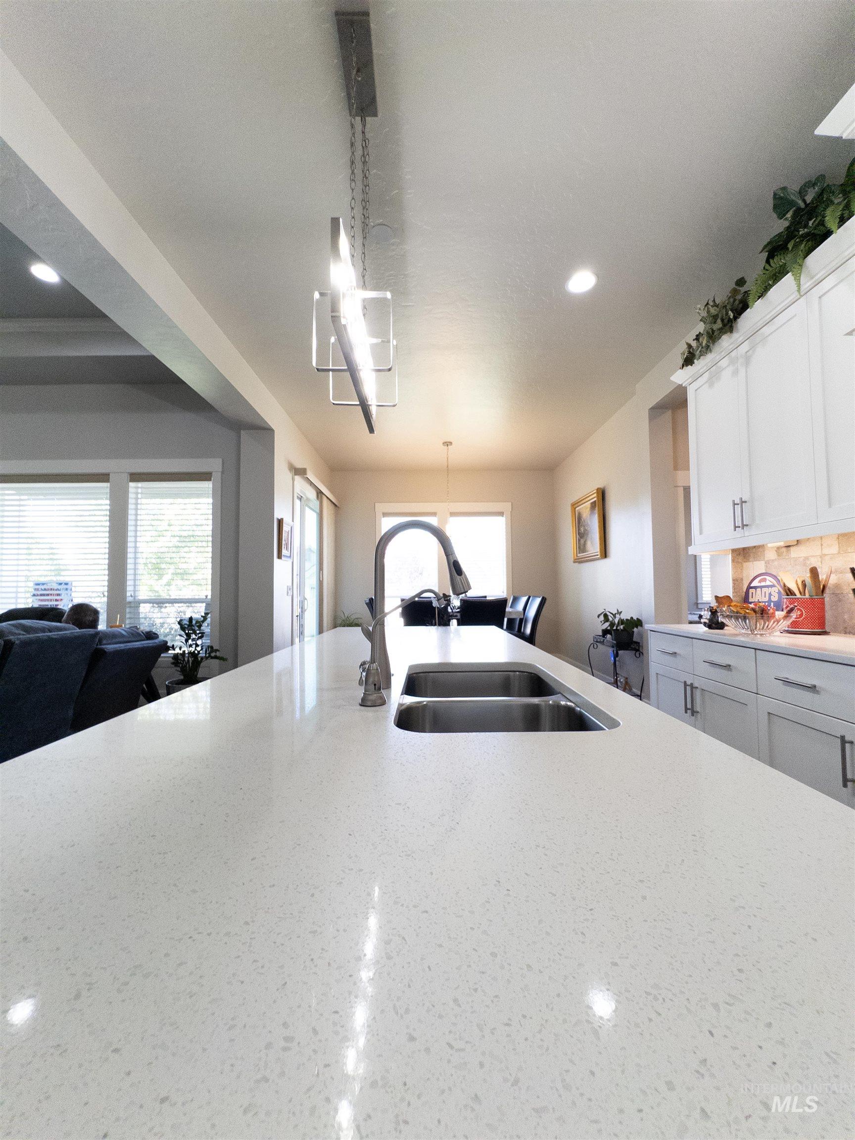 4577 North Comiso Place Meridian, ID 83646 - Photo 47 of 47 Kitchen featuring recessed lighting, open floor plan, light stone counters, white cabinetry, and decorative light fixtures