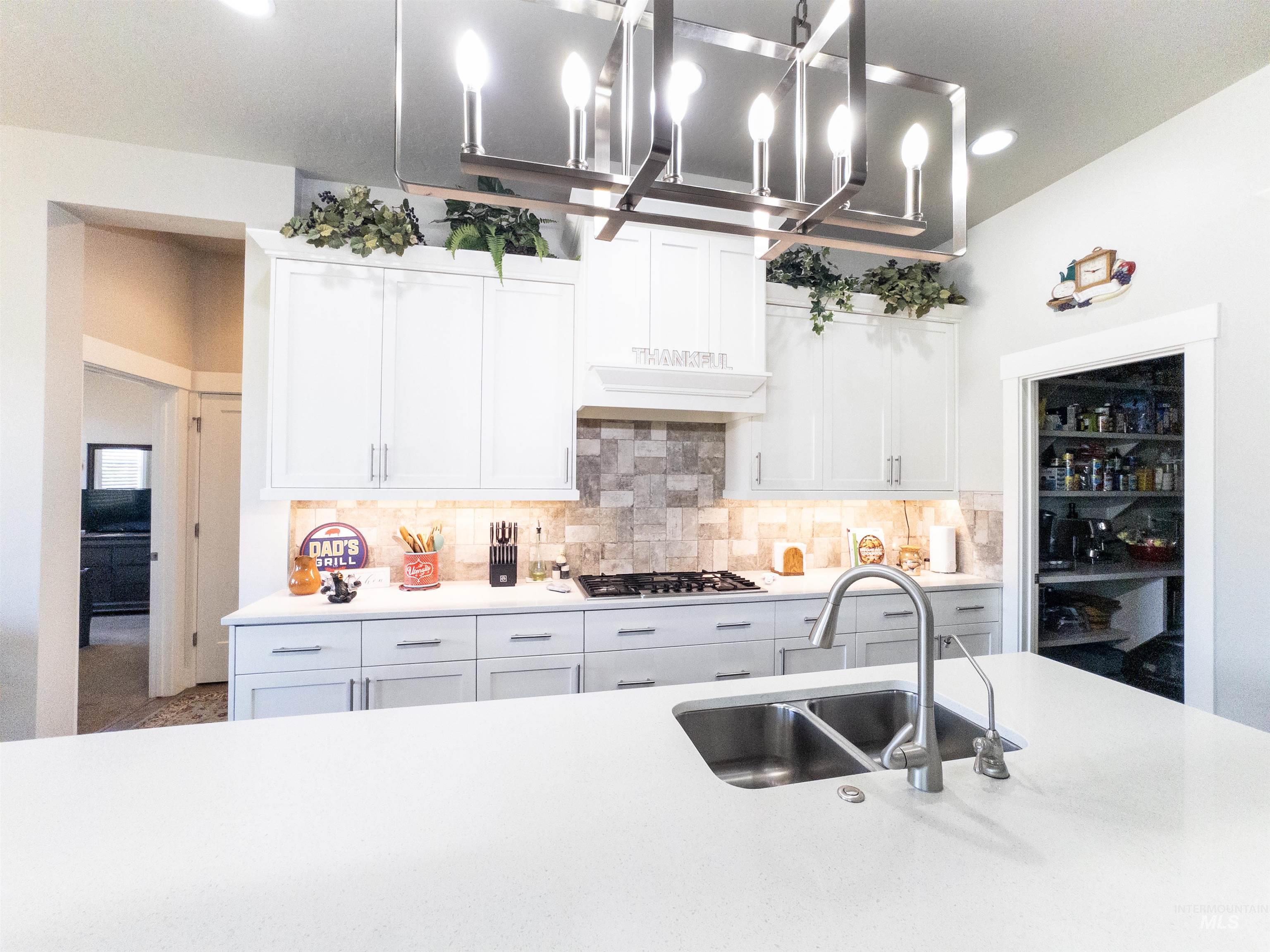 4577 North Comiso Place Meridian, ID 83646 - Photo 15 of 47 Kitchen with white cabinets, backsplash, recessed lighting, light stone countertops, and stainless steel gas stovetop