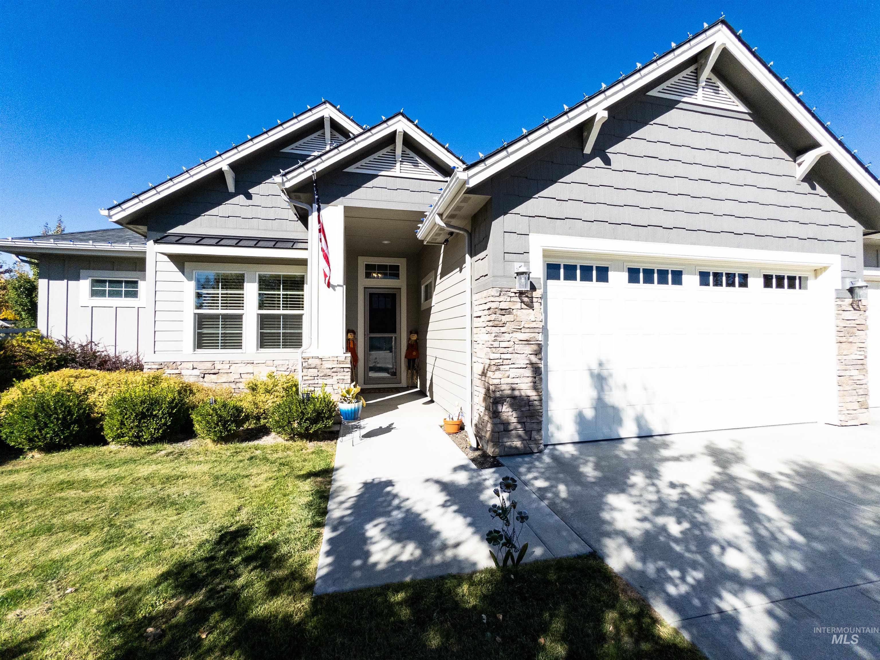 4577 North Comiso Place Meridian, ID 83646 - Photo 2 of 47 Craftsman-style house with stone siding, driveway, a front lawn, and a garage