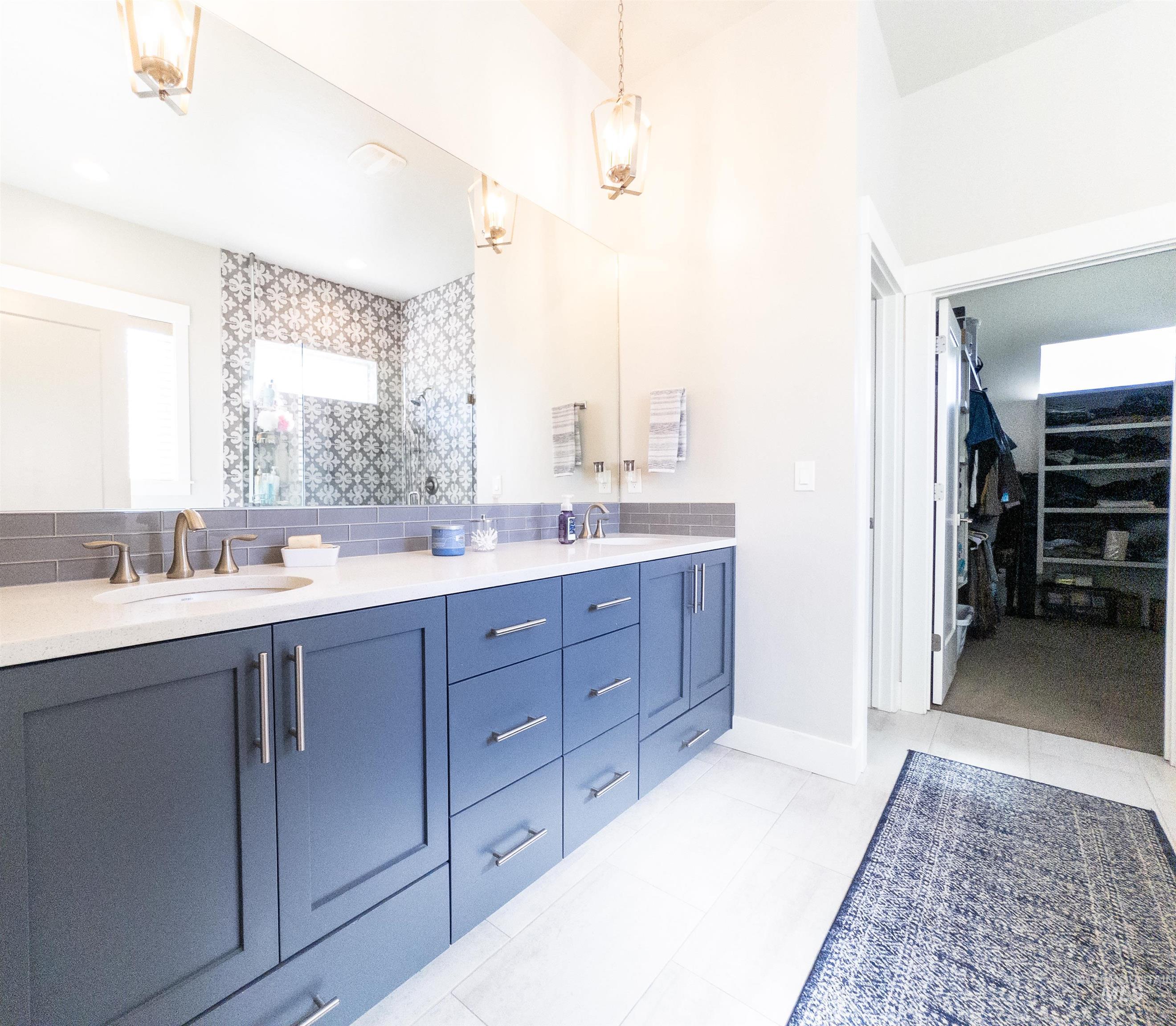 4577 North Comiso Place Meridian, ID 83646 - Photo 30 of 47 Bathroom featuring double vanity, a spacious closet, light tile patterned floors, and a tile shower