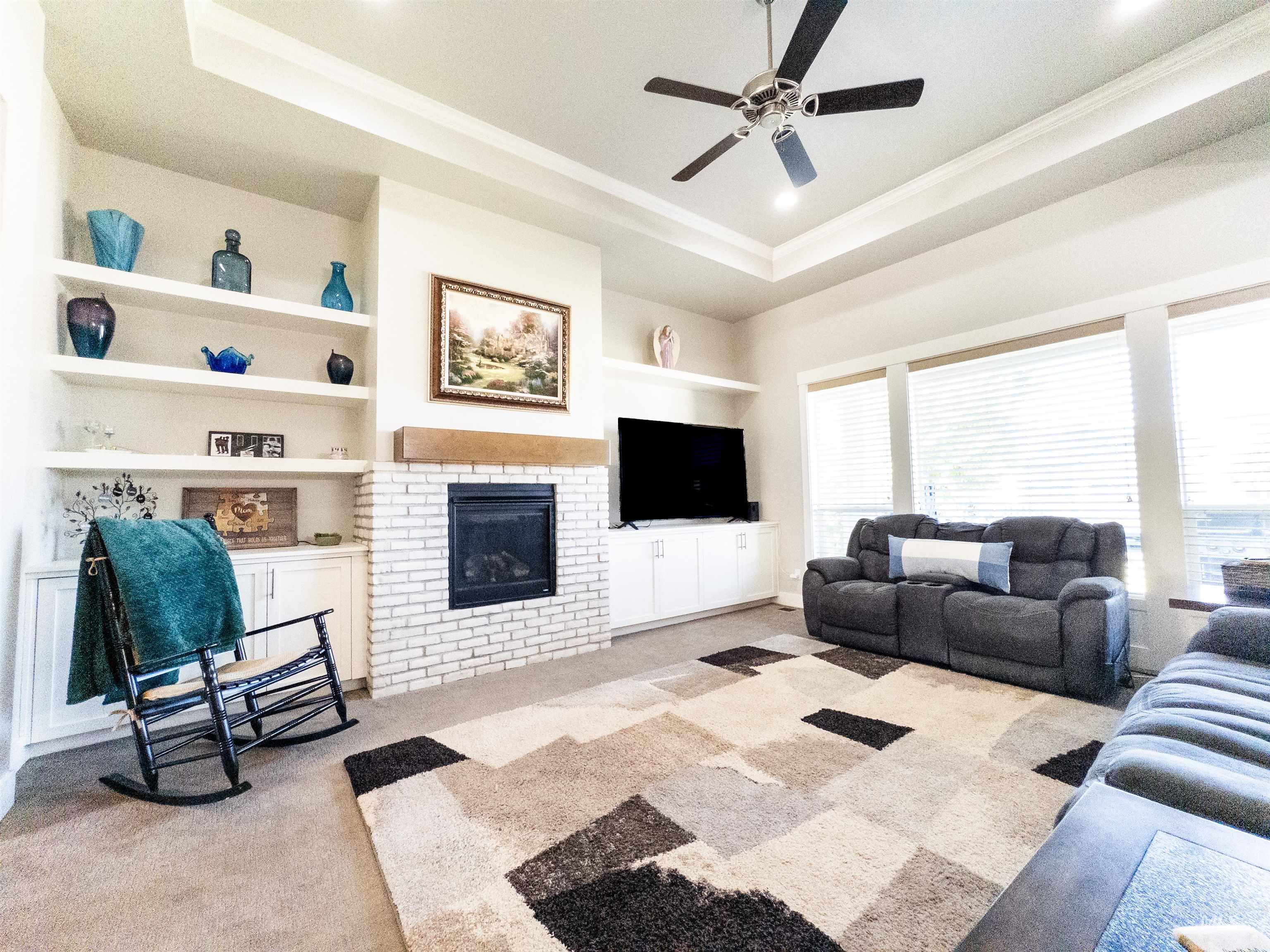 4577 North Comiso Place Meridian, ID 83646 - Photo 8 of 47 Living room with built in shelves, a tray ceiling, a fireplace, light carpet, and crown molding