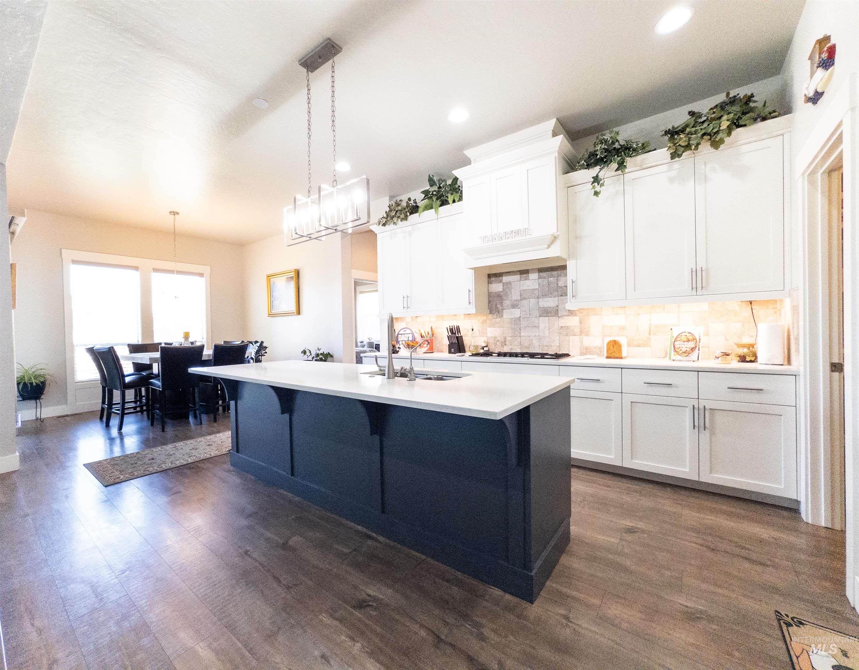 4577 North Comiso Place Meridian, ID 83646 - Photo 10 of 47 Kitchen with white cabinets, decorative light fixtures, backsplash, dark wood-style flooring, and recessed lighting