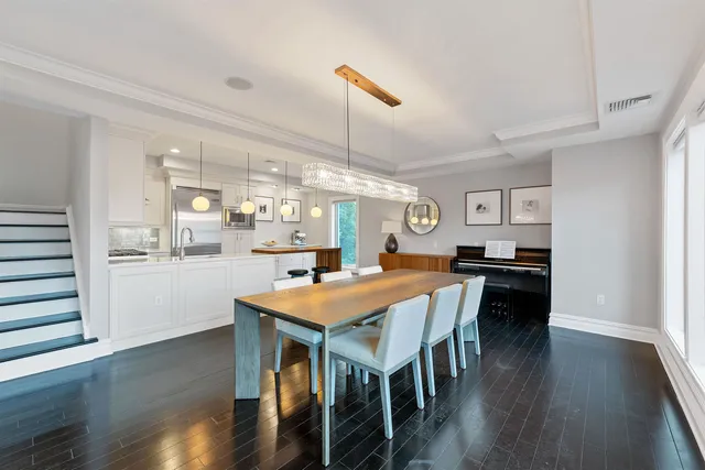 a dining room with wooden floor a chandelier a wooden table and chairs