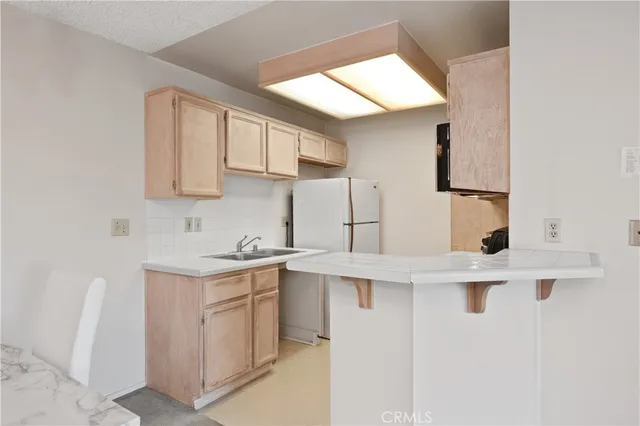 a kitchen with a sink a stove a refrigerator and white cabinets