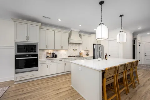 a kitchen with stainless steel appliances kitchen island granite countertop a sink a stove a refrigerator and white cabinets