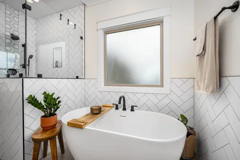 a white bath tub sitting next to a white sink and a mirror