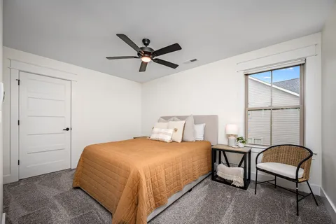 a bedroom with a bed a chair and a large window