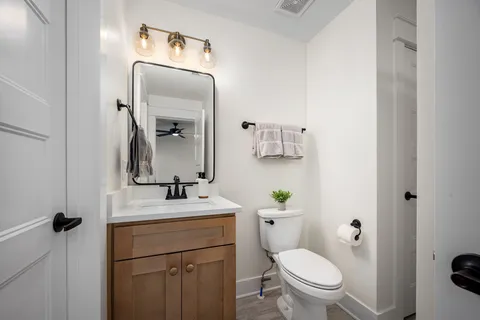 a bathroom with a toilet sink vanity and mirror