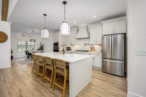 a kitchen with stainless steel appliances granite countertop a sink a stove a refrigerator and island with wooden floor