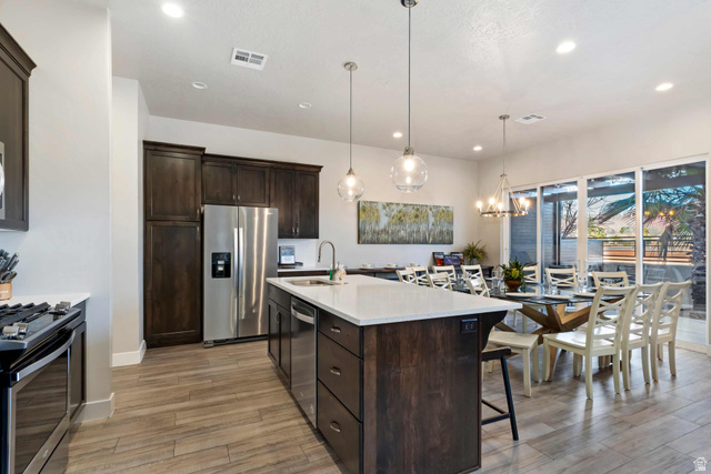 2600 Ocotillo Way, Unit 31 Santa Clara, UT 84765 - Photo 10 of 73 Open-concept kitchen and dining area featuring a central island with a white countertop, dark wood-finish cabinetry, stainless steel appliances, and wood-finish flooring