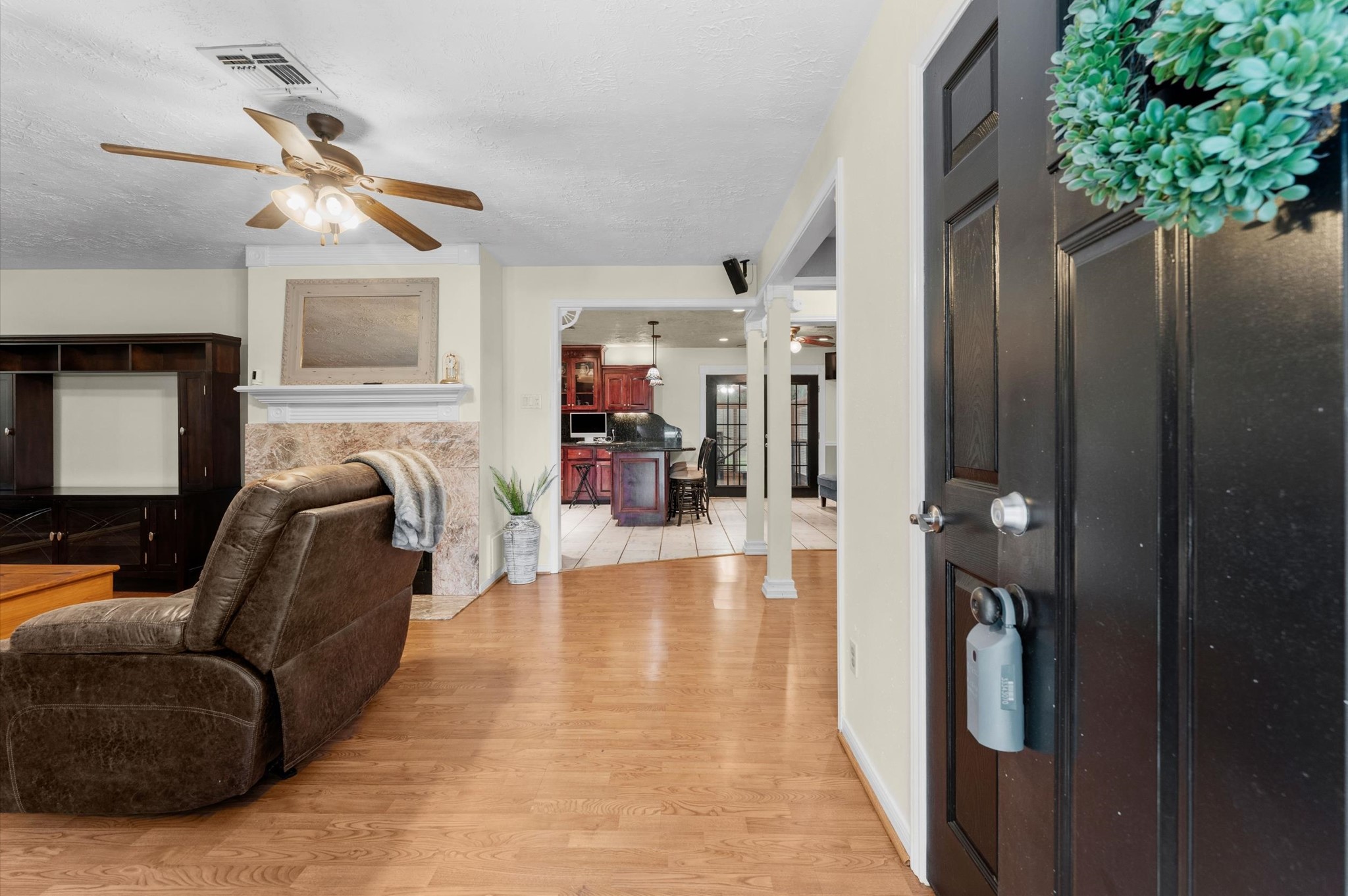 22634 Park Road Tomball, TX 77377 - Photo 4 of 29 Step into a warm and inviting living space featuring a cozy fireplace, laminate floors, and a seamless flow into a well-appointed kitchen and dining area.