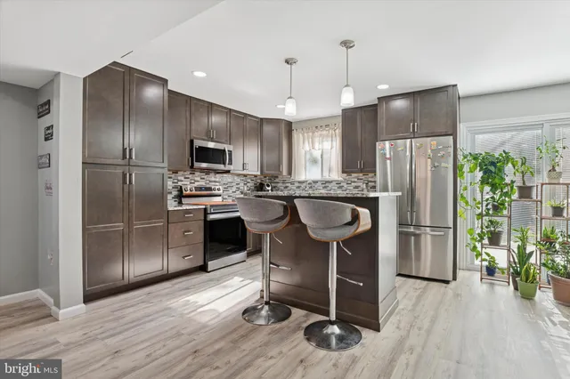 a kitchen with stainless steel appliances a refrigerator a stove a sink cabinets and wooden floor