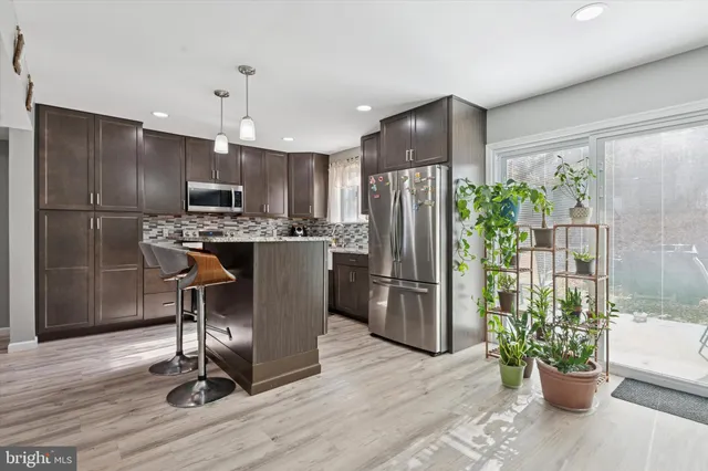 a kitchen with stainless steel appliances a refrigerator a stove a sink cabinets and a dining table