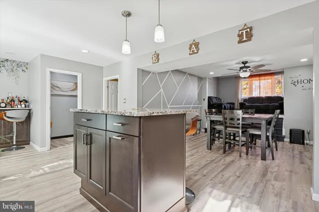 a kitchen with stainless steel appliances kitchen island granite countertop a table chairs and a refrigerator