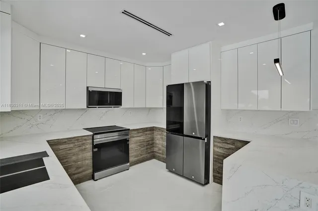 a kitchen with stainless steel appliances granite countertop a refrigerator a stove and a sink