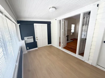 a view of an empty room with a window and wooden floor