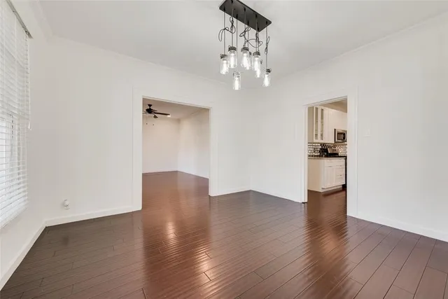 an empty room with wooden floor and chandelier