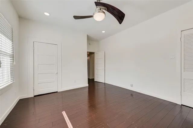 an empty room with wooden floor cabinet and windows