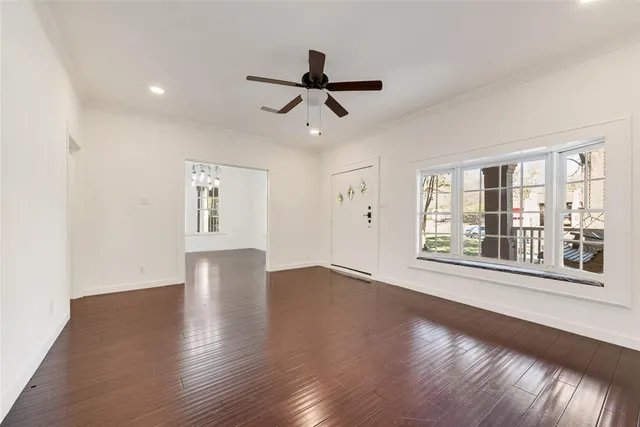 a view of empty room with wooden floor and fan