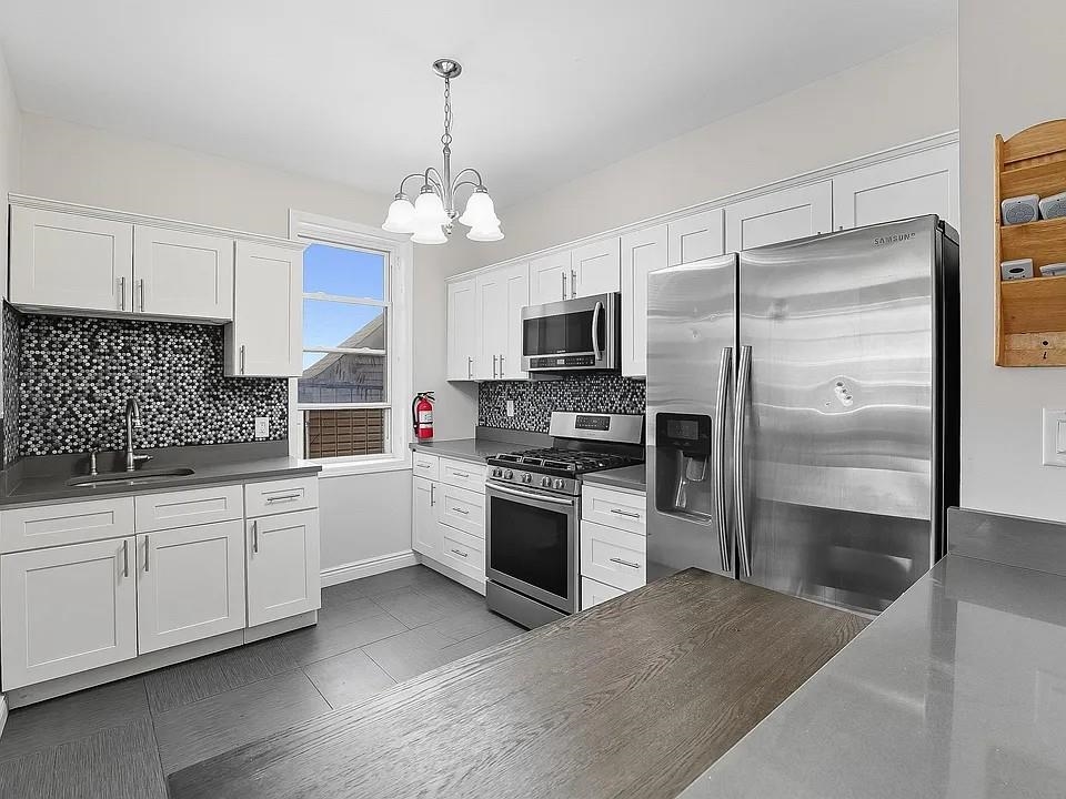 7603 1st Avenue, Unit B2 North Bergen, NJ 07047 - Photo 3 of 4 a kitchen with stainless steel appliances granite countertop a refrigerator a stove a sink dishwasher a oven with white cabinets and wooden floor