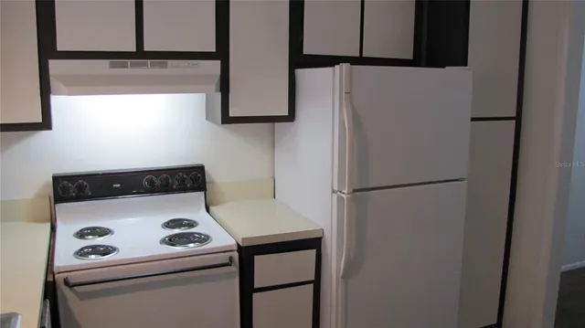 a white refrigerator freezer and a stove sitting inside of a kitchen