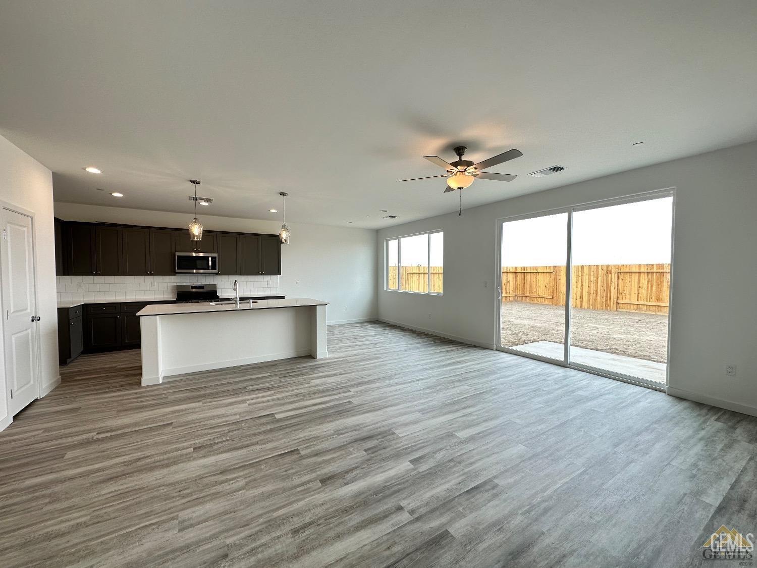 Undisclosed Address Bakersfield, CA 93311 - Photo 7 of 7 a view of an empty room with a kitchen and wooden floor