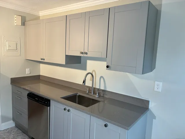 a kitchen with stainless steel appliances granite countertop a sink a stove and white cabinets with wooden floor