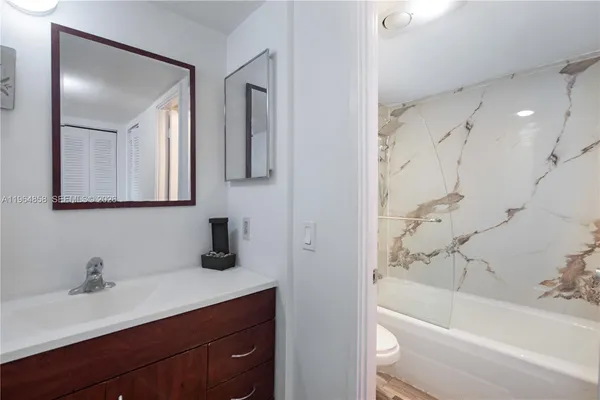 a bathroom with a bathtub shower sink vanity and mirror