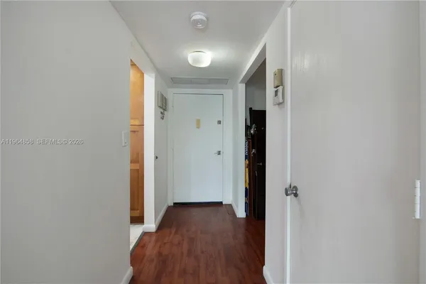 a view of a hallway with wooden floor and a bathroom