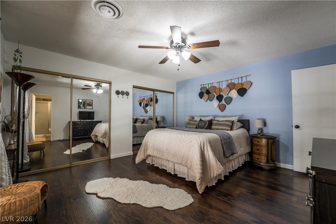 1324 Appaloosa Road Boulder City, NV 89005 - Photo 19 of 42 Rich hardwood floors complement a spacious bedroom featuring mirrored closets and a ceiling fan.