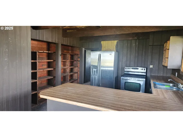 a view of kitchen and empty room with wooden floor