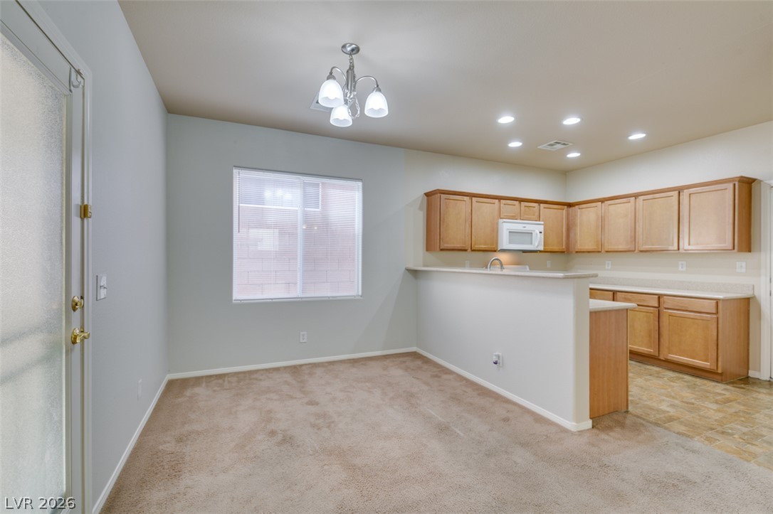8937 Caledon Ridge Court Las Vegas, NV 89149 - Photo 14 of 43 A streamlined open-concept space features warm wood cabinetry and a convenient breakfast bar for casual dining.