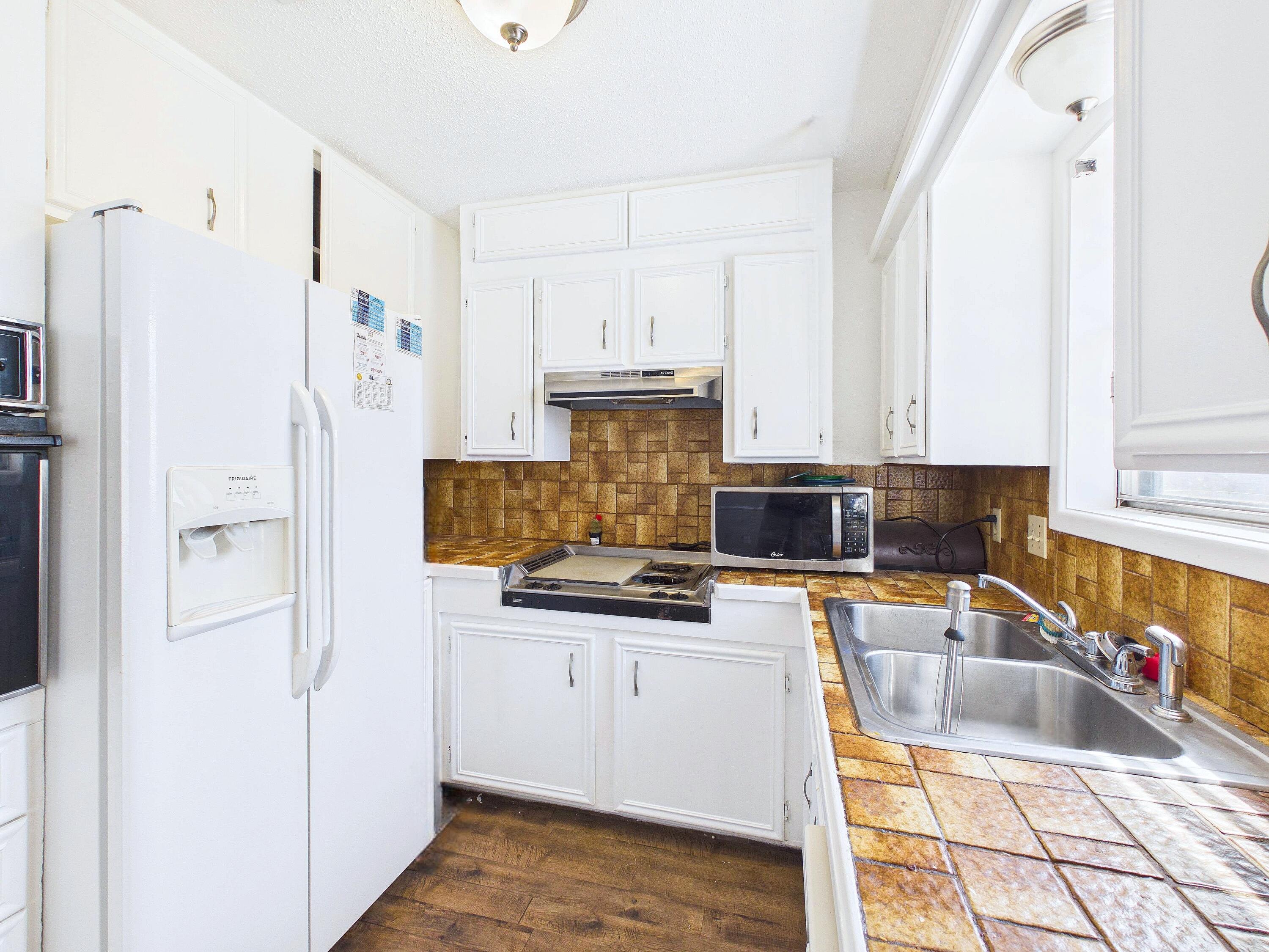 4825 10th Street Lubbock, TX 79416 - Photo 11 of 27 a kitchen with granite countertop a sink stove and refrigerator