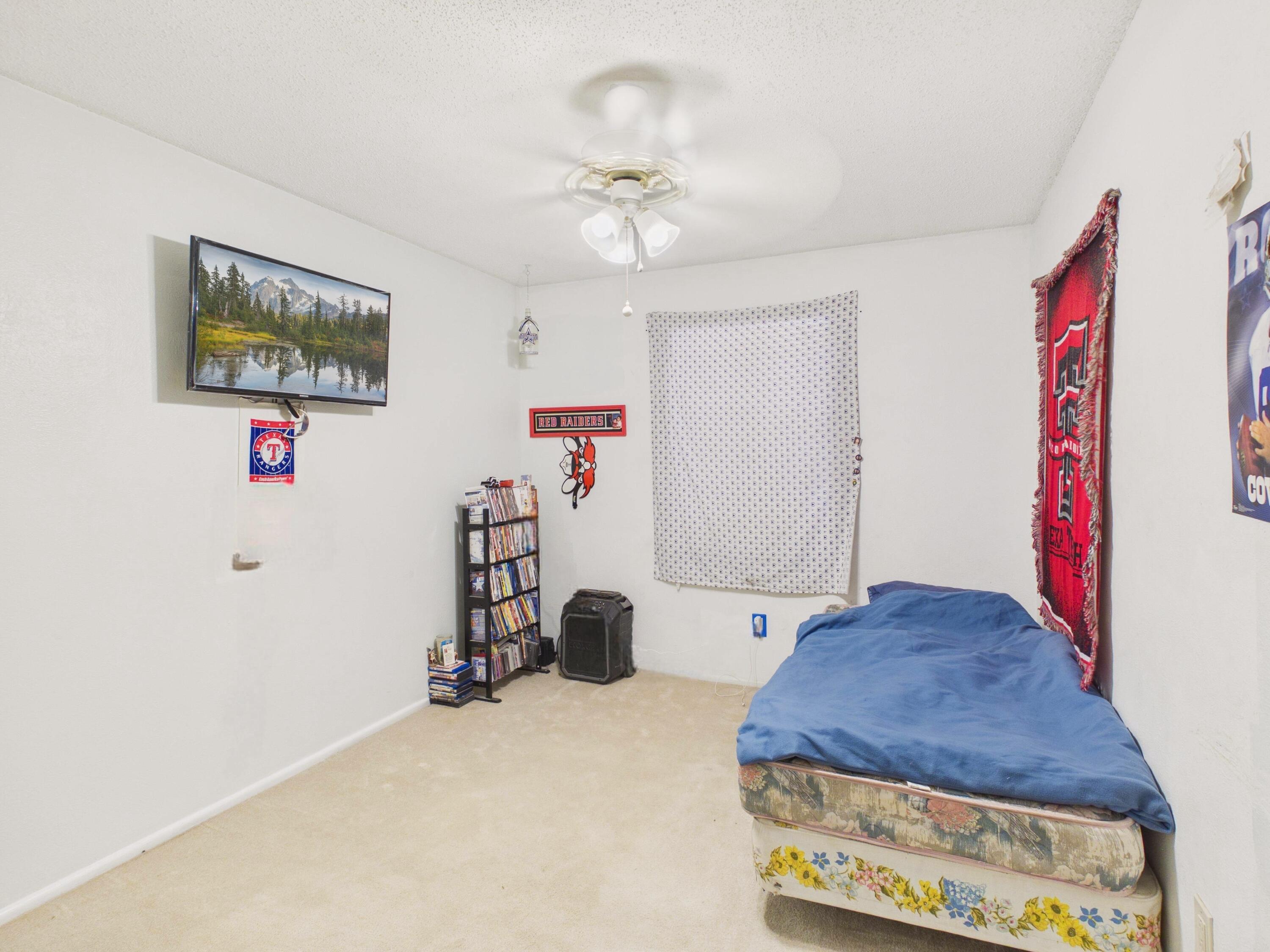 4825 10th Street Lubbock, TX 79416 - Photo 15 of 27 a bedroom with a bed and a chandelier