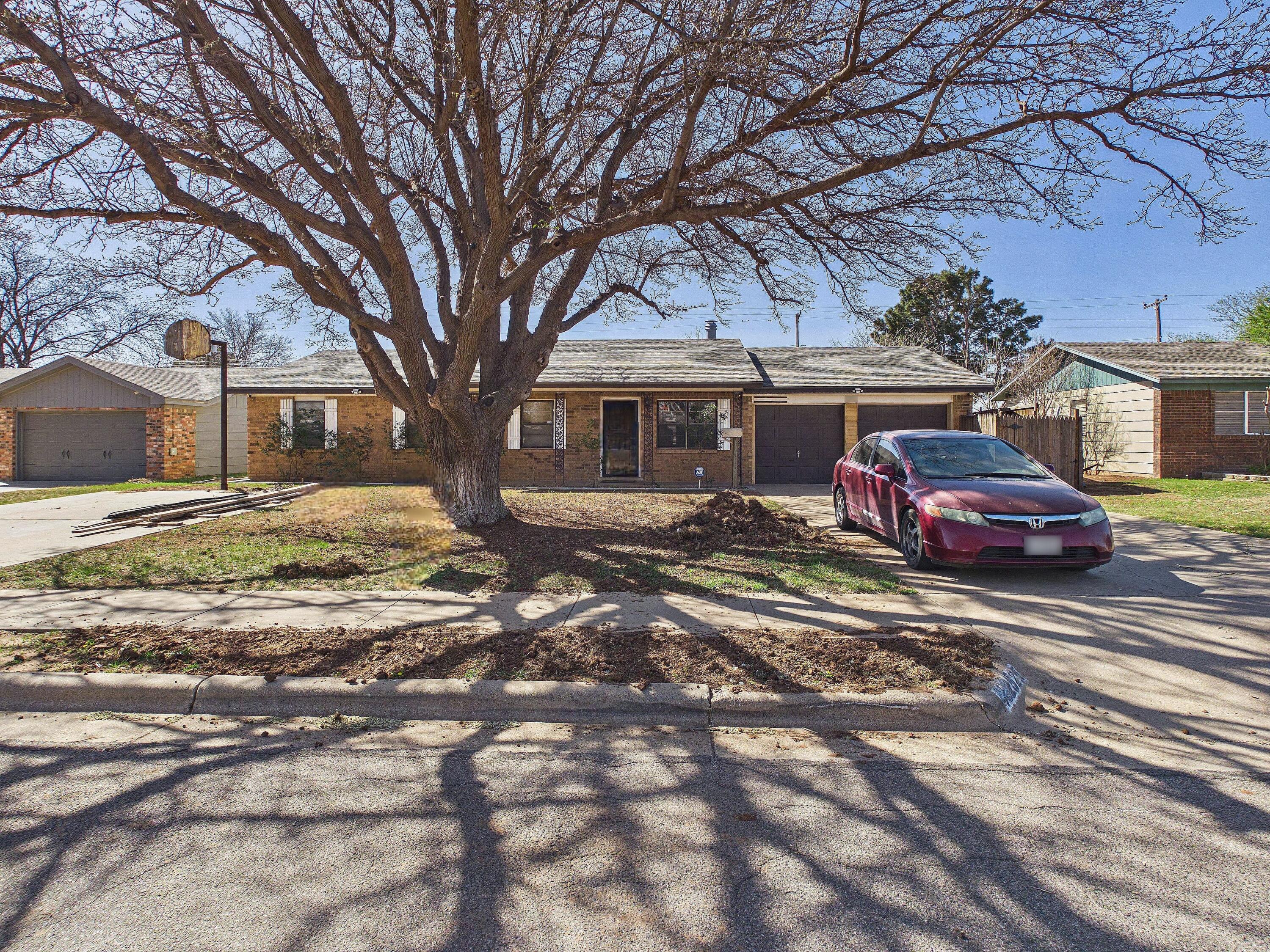 4825 10th Street Lubbock, TX 79416 - Photo 2 of 27 a red car parked in front of a white house